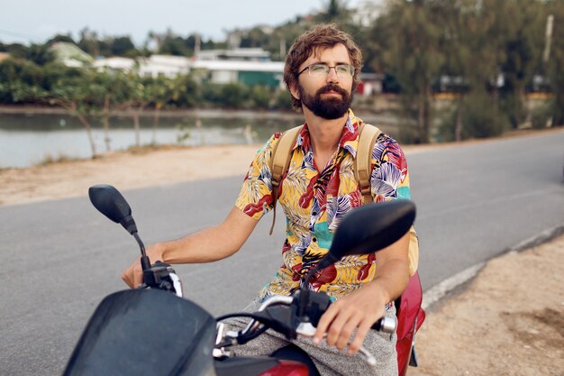 Hombre con barba en colorida camisa tropical sentado en moto