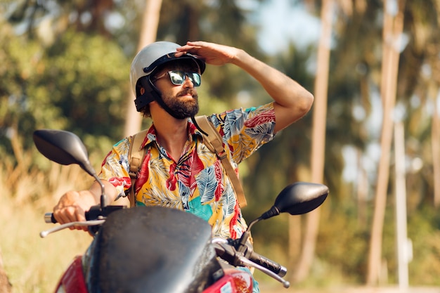 Hombre con barba en colorida camisa tropical sentado en moto