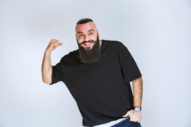 Hombre con barba demostrando sus puños y músculos del brazo.