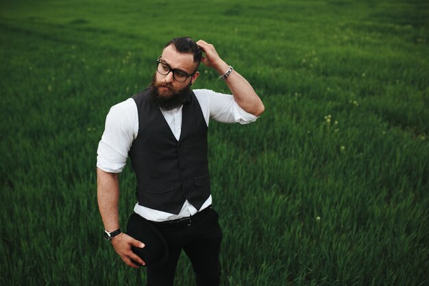 Un hombre con barba y gafas de sol caminando por el campo.