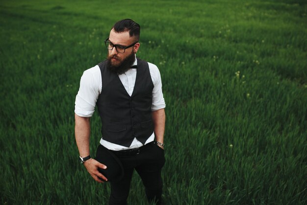 Un hombre con barba y gafas de sol caminando por el campo.