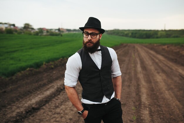 Un hombre con barba y gafas de sol caminando por el campo.