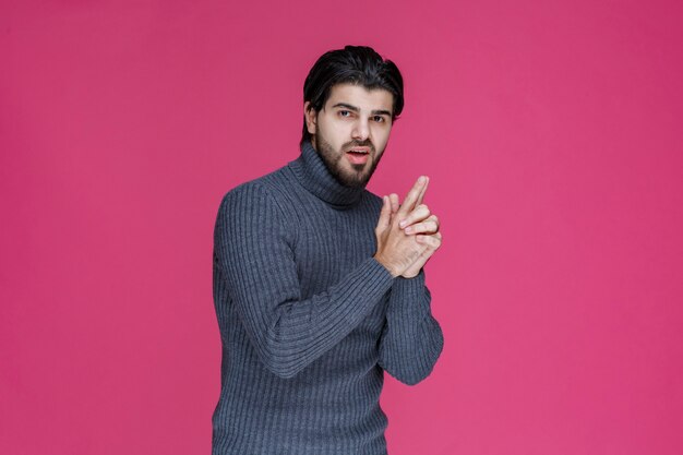 Hombre con barba haciendo un signo de pistola de mano.