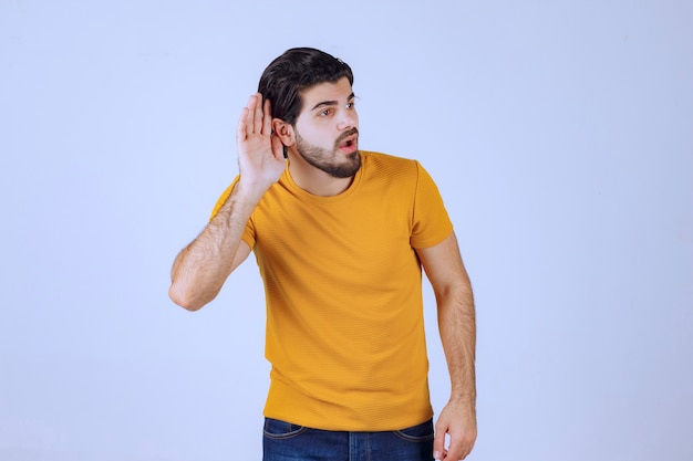 Foto gratuita hombre con barba mostrando su oído y tratando de escuchar atentamente