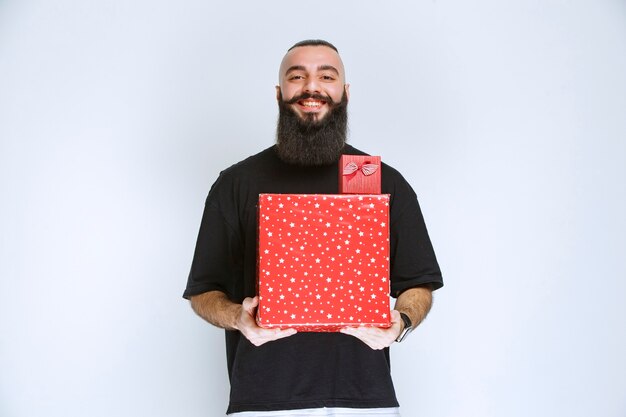 Hombre con barba ofreciendo caja de regalo roja