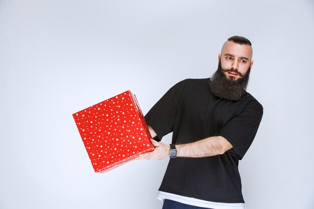 Hombre con barba ofreciendo caja de regalo roja