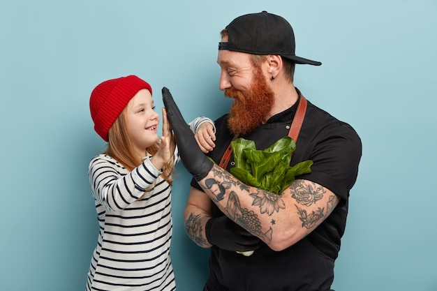 Foto gratuita hombre con barba pelirroja en delantal y guantes chocando los cinco con su hija