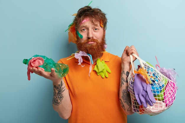 Hombre con barba pelirroja sosteniendo bolsas con residuos plásticos