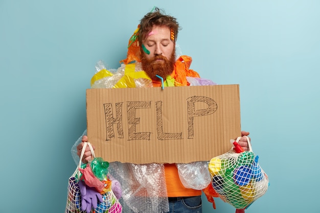 Foto gratuita hombre con barba pelirroja sosteniendo bolsas con residuos plásticos