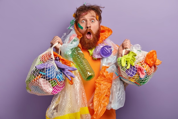 Foto gratuita hombre con barba pelirroja sosteniendo bolsas con residuos plásticos