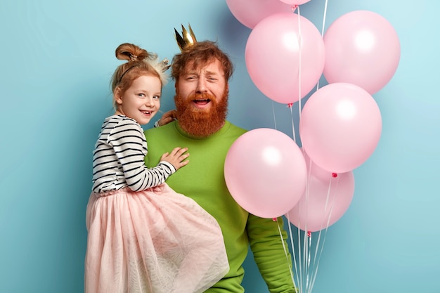 Hombre con barba pelirroja y su hija con accesorios de fiesta