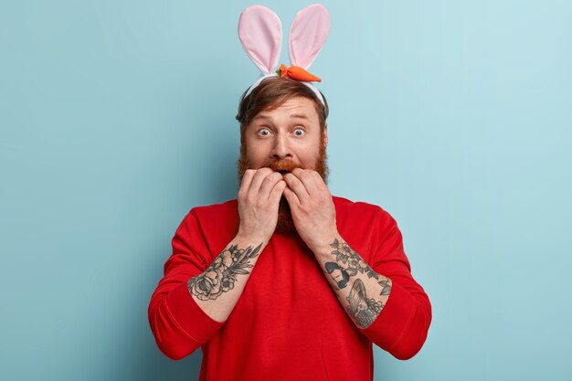 Hombre con barba pelirroja vistiendo ropas coloridas y orejas de conejo