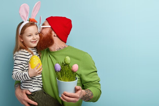 Hombre con barba pelirroja vistiendo ropas coloridas y sosteniendo a su hija