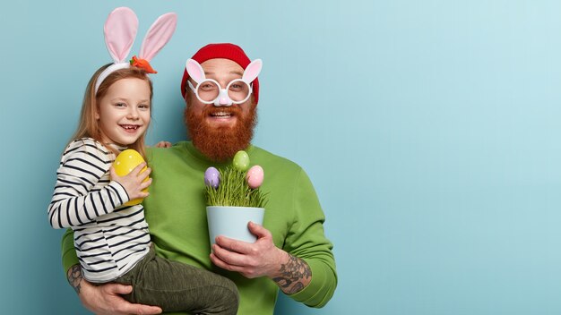 Hombre con barba pelirroja vistiendo ropas coloridas y sosteniendo a su hija