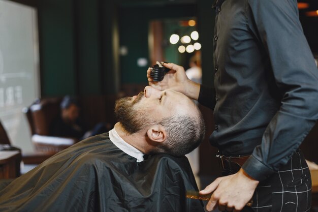 Hombre con barba. Peluquería con cliente. Hombre con peine y tijeras