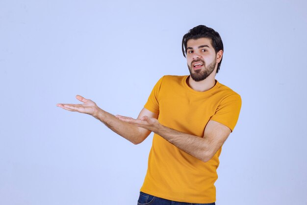 Hombre con barba presentando algo en su mano abierta