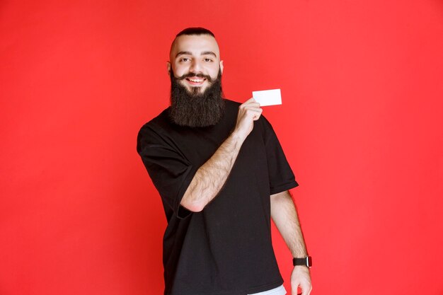 Hombre con barba presentando su tarjeta de visita.