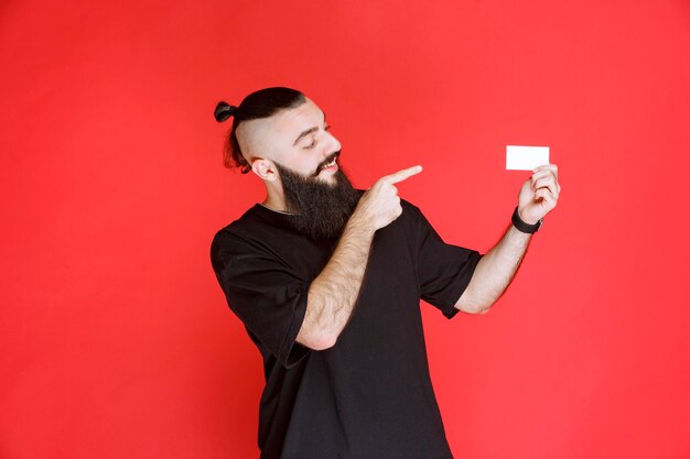 Hombre con barba presentando su tarjeta de visita.