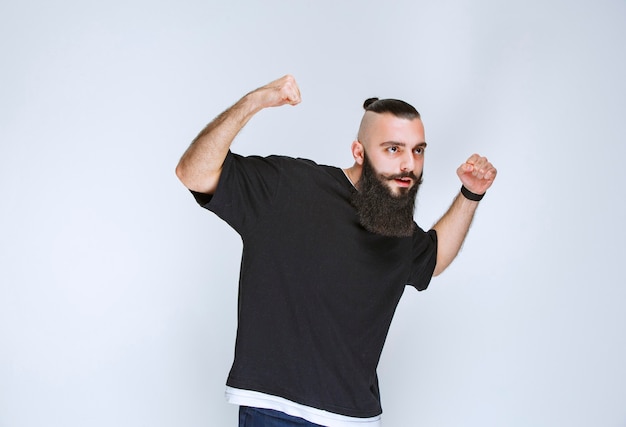 Hombre con barba que demuestra los músculos de sus brazos y se siente poderoso.