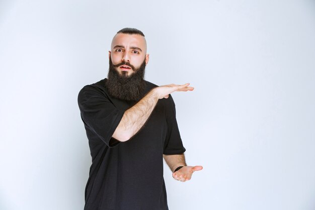 Hombre con barba que muestra las dimensiones de un objeto.