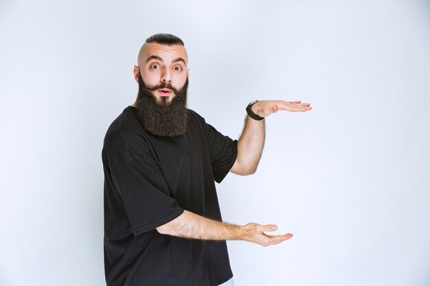 Hombre con barba que muestra las dimensiones de un objeto.