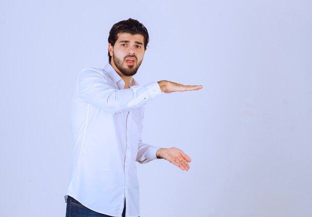 Hombre con barba que muestra las medidas estimadas de un objeto.