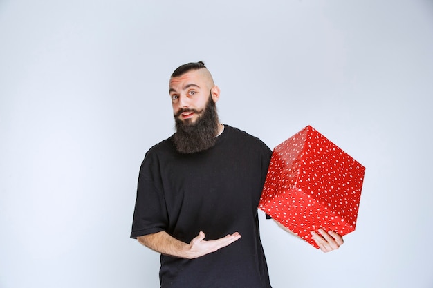 Hombre con barba sosteniendo una caja de regalo roja
