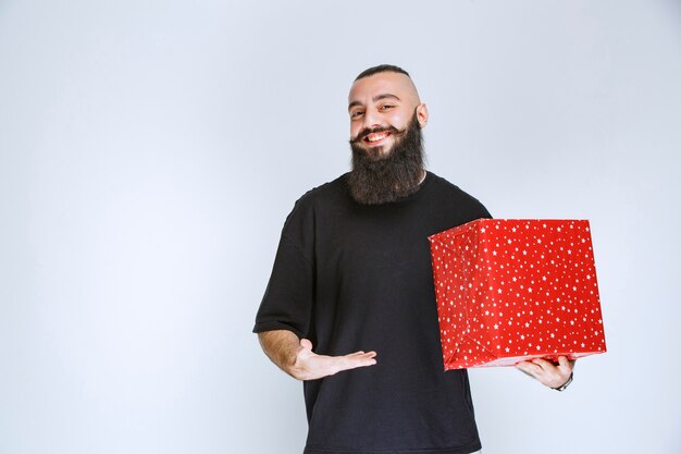 Hombre con barba sosteniendo una caja de regalo roja