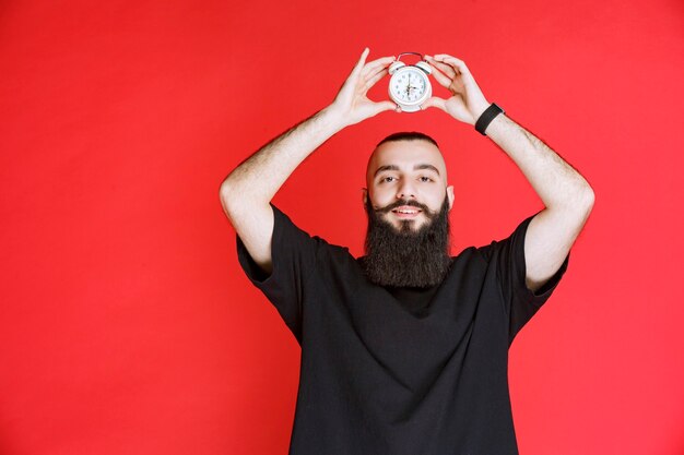 Hombre con barba sosteniendo un despertador y disfrutando del producto.