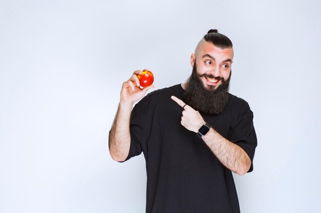 Hombre con barba sosteniendo una manzana roja o melocotón.