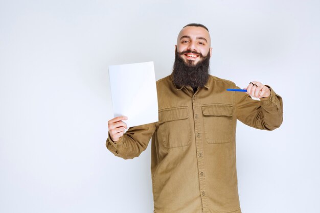 Hombre con barba sosteniendo su lista de informes y esperando con confianza.