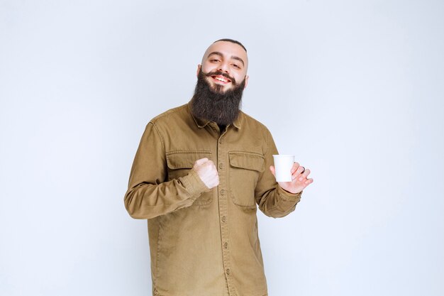 Hombre con barba sosteniendo una taza de café y disfrutando del sabor.