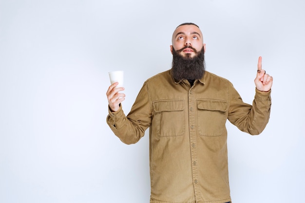 Hombre con barba sosteniendo una taza de café y pensando.