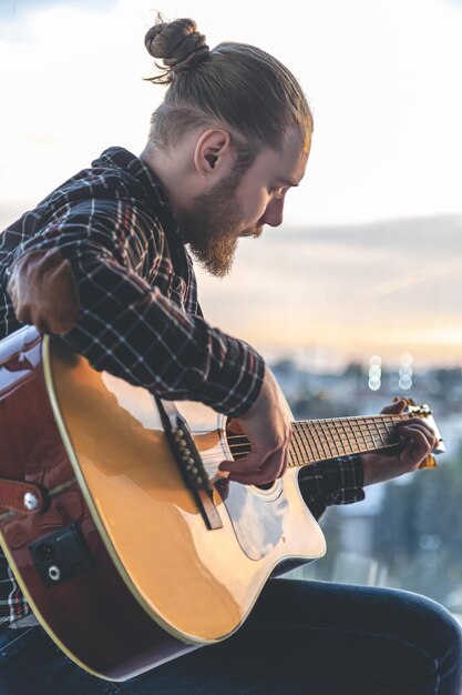 Un hombre con barba toca la guitarra acústica.