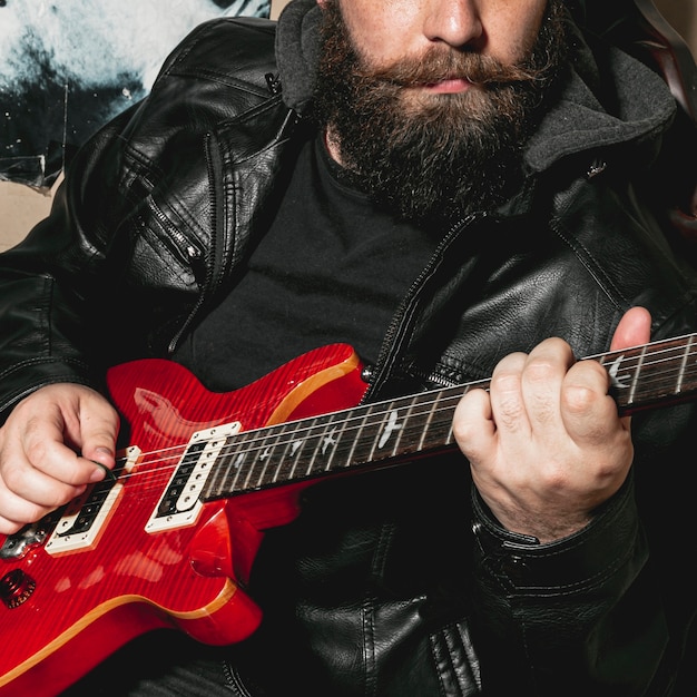 Hombre de barba tocando guitarra roja vintage