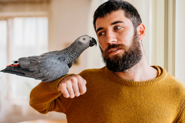 Foto gratuita hombre barbudo acariciando lindo pájaro