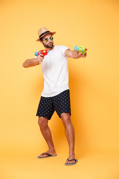 Foto gratuita hombre barbudo apuntando con pistola de agua