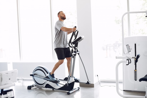 Hombre barbudo con bicicleta de spinning en la sala de fisioterapia