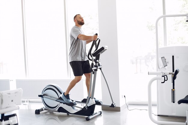 Hombre barbudo con bicicleta de spinning en la sala de fisioterapia