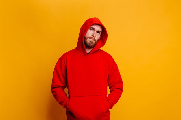 Hombre barbudo brutal guapo feliz con sudadera con capucha de lana de moda de invierno rojo cálido