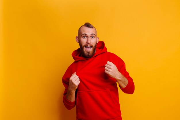 Hombre barbudo brutal guapo feliz con sudadera con capucha de lana de moda de invierno rojo cálido