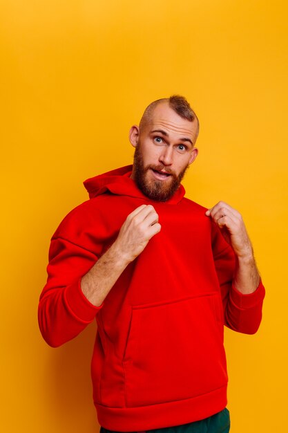 Hombre barbudo brutal guapo feliz con sudadera con capucha de lana de moda de invierno rojo cálido