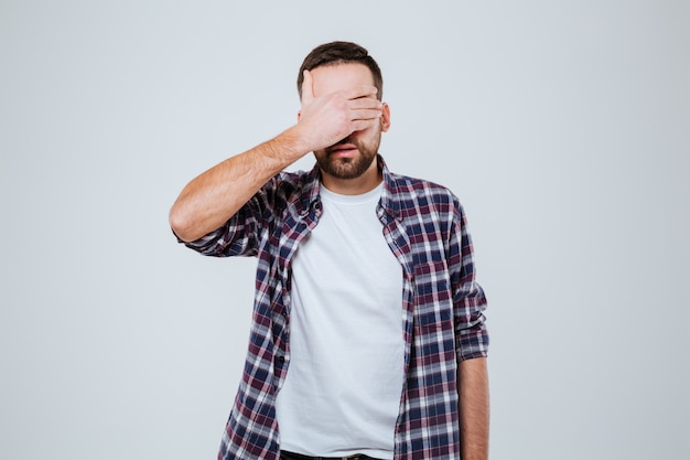 Hombre barbudo en camisa cubriendo sus ojos