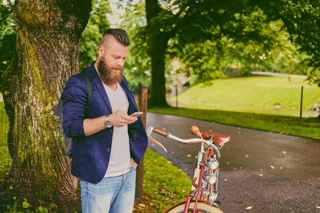 Hombre barbudo casual en un parque habla por teléfono inteligente.