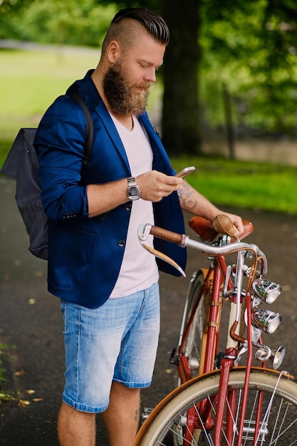 Hombre barbudo casual en un parque habla por teléfono inteligente.