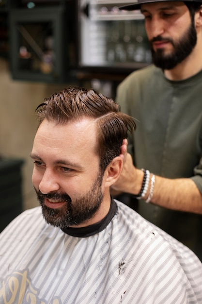 Hombre barbudo cortándose el pelo en la peluquería