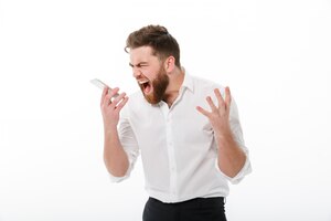Foto gratuita hombre barbudo enojado en ropa de negocios gritando al teléfono inteligente