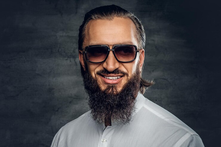 Foto gratuito hombre barbudo con estilo en una camisa blanca y gafas de sol aislado sobre fondo gris.