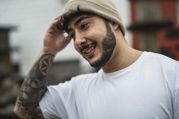 Foto gratuita hombre barbudo europeo fresco con tatuajes en el brazo sonriendo positivamente