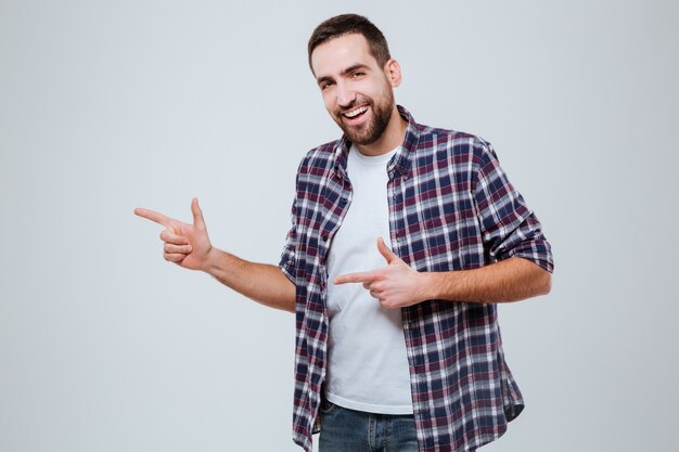 Hombre barbudo feliz en camisa apuntando lejos